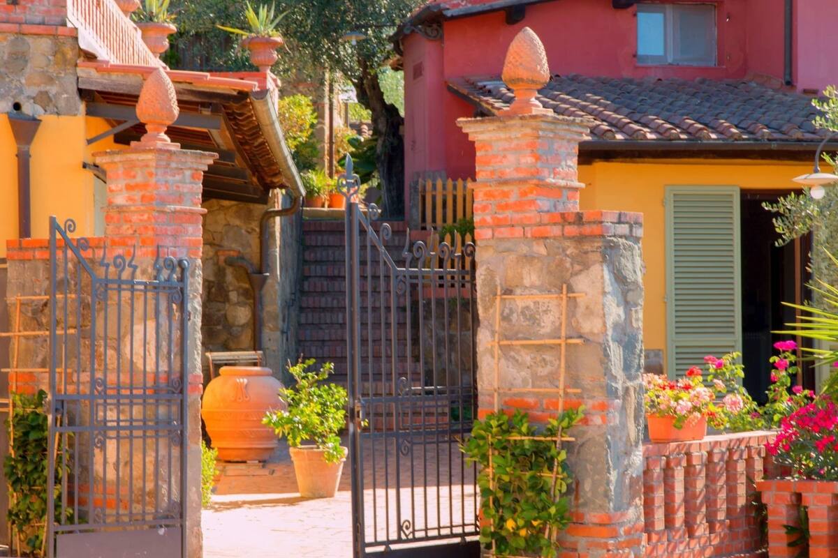 Un arco de piedra tradicional con una valla de metal, un muro de ladrillo y un tejado de tejas.