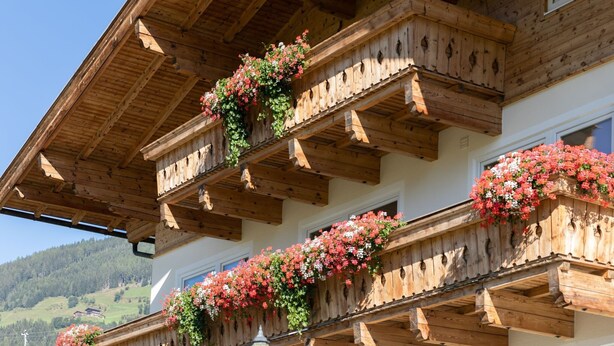A wooden chalet with multiple balconies adorned with flower boxes.