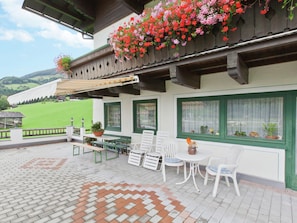 Eine Terrasse mit Sitzgelegenheiten im Freien, einem Tisch und hängenden Blumenkörben.