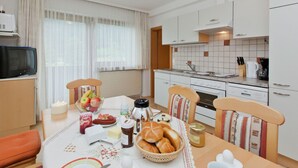 A modern kitchen with white cabinets, a Bosch oven, and a dining area with a table set for breakfast.
