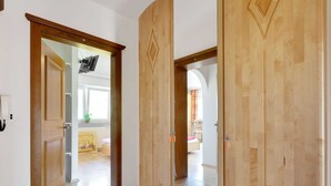 A hallway with wooden doors leading to a room with a bed and a window.