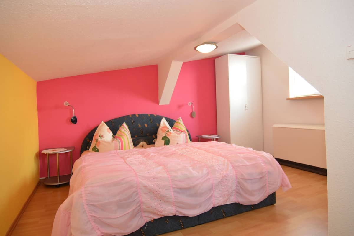 A bedroom with a bed, a dresser, a nightstand, and a window.