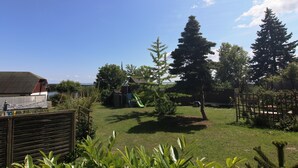 A backyard with a slide, a wooden fence, and a view of the water. - Spacious Appartment in Wilhelmshof Near Lake (Usedom)