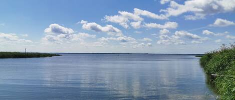 A calm body of water with a clear sky and scattered clouds.