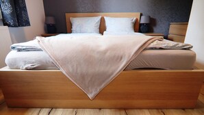 Un lit bien fait, avec une tête de lit en bois, deux lampes de chevet et un coussin à motifs.