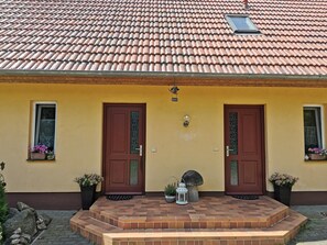 A building with a yellow facade, two brown doors, and a tiled roof. - Spacious Appartment in Wilhelmshof Near Lake (Usedom)
