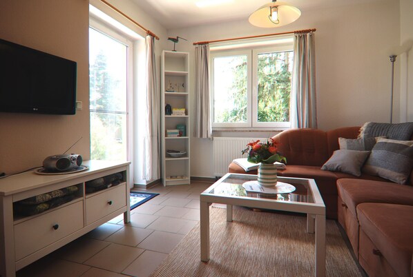 A living room with a television, a sofa, a coffee table, and a bookshelf. - Spacious Appartment in Wilhelmshof Near Lake (Usedom)