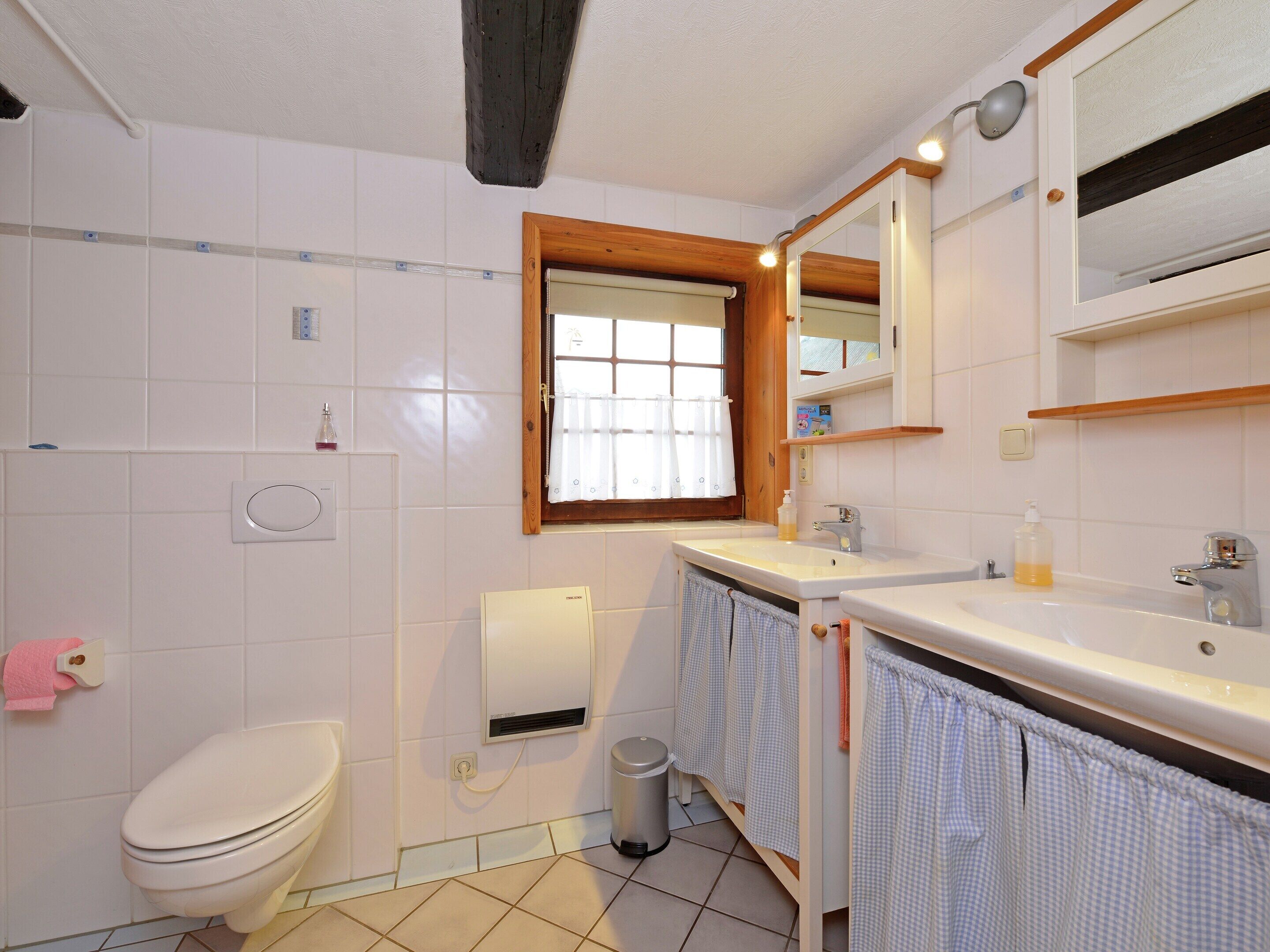 Ein Badezimmer mit Toilette, Waschbecken, Spiegel und Fenster.