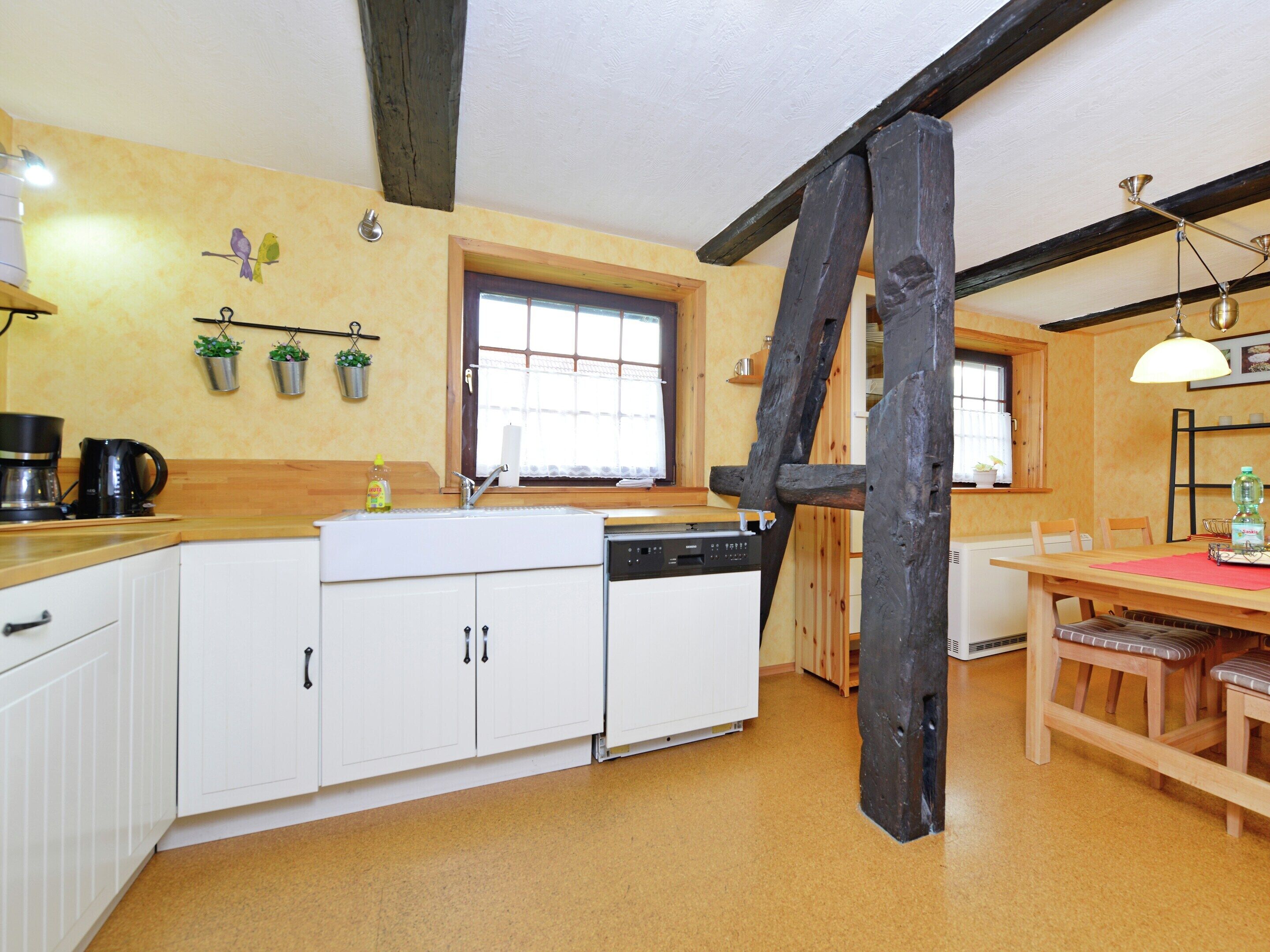 A kitchen with white cabinets, a wooden table, and a hanging light fixture.