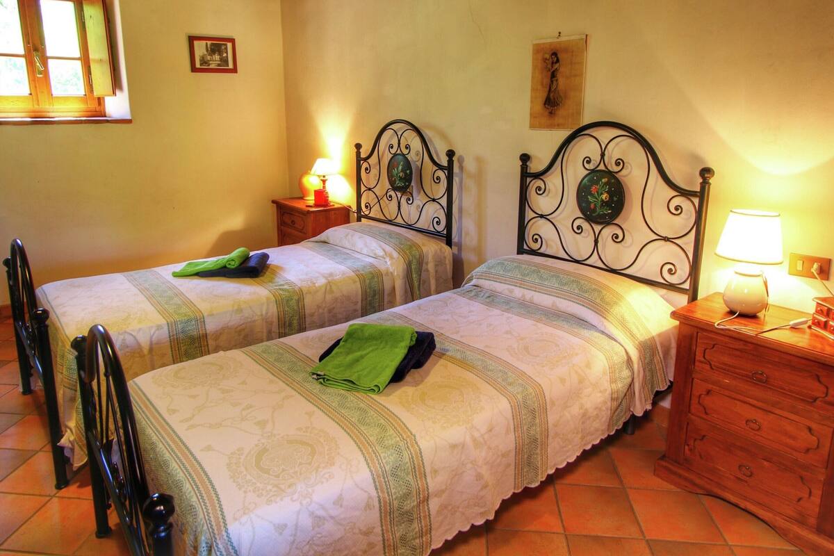 A double bed with a metal frame and a wooden nightstand with a lamp.