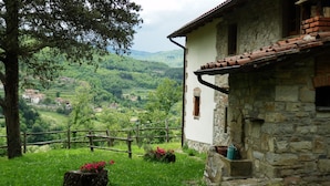 A stone building with a tiled roof, surrounded by a wooden fence and lush greenery. - Alluring Farmhouse in Ortignano With Swimming Pool (Ortignano Raggiolo)