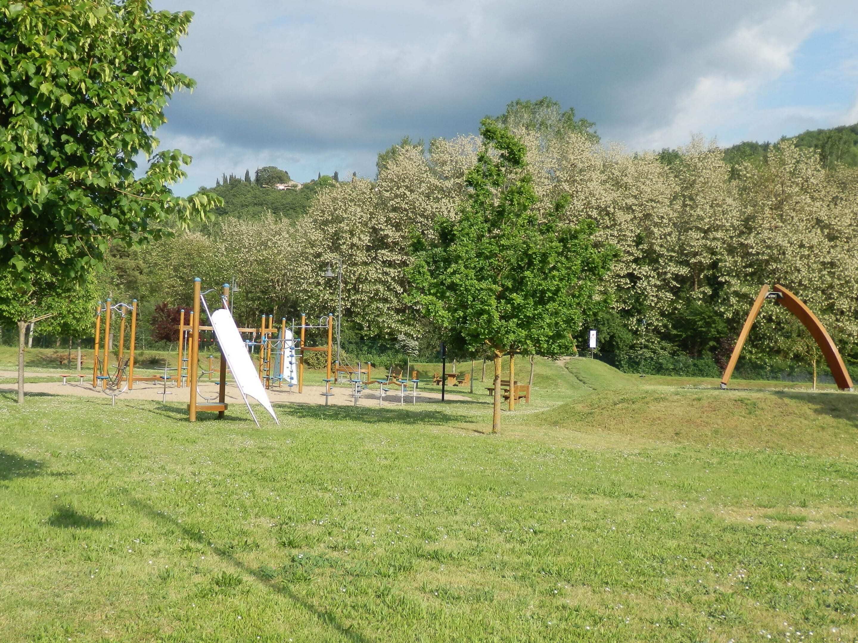 Een speeltuin met diverse speeltoestellen, een picknickplaats en een heuvel met bomen.