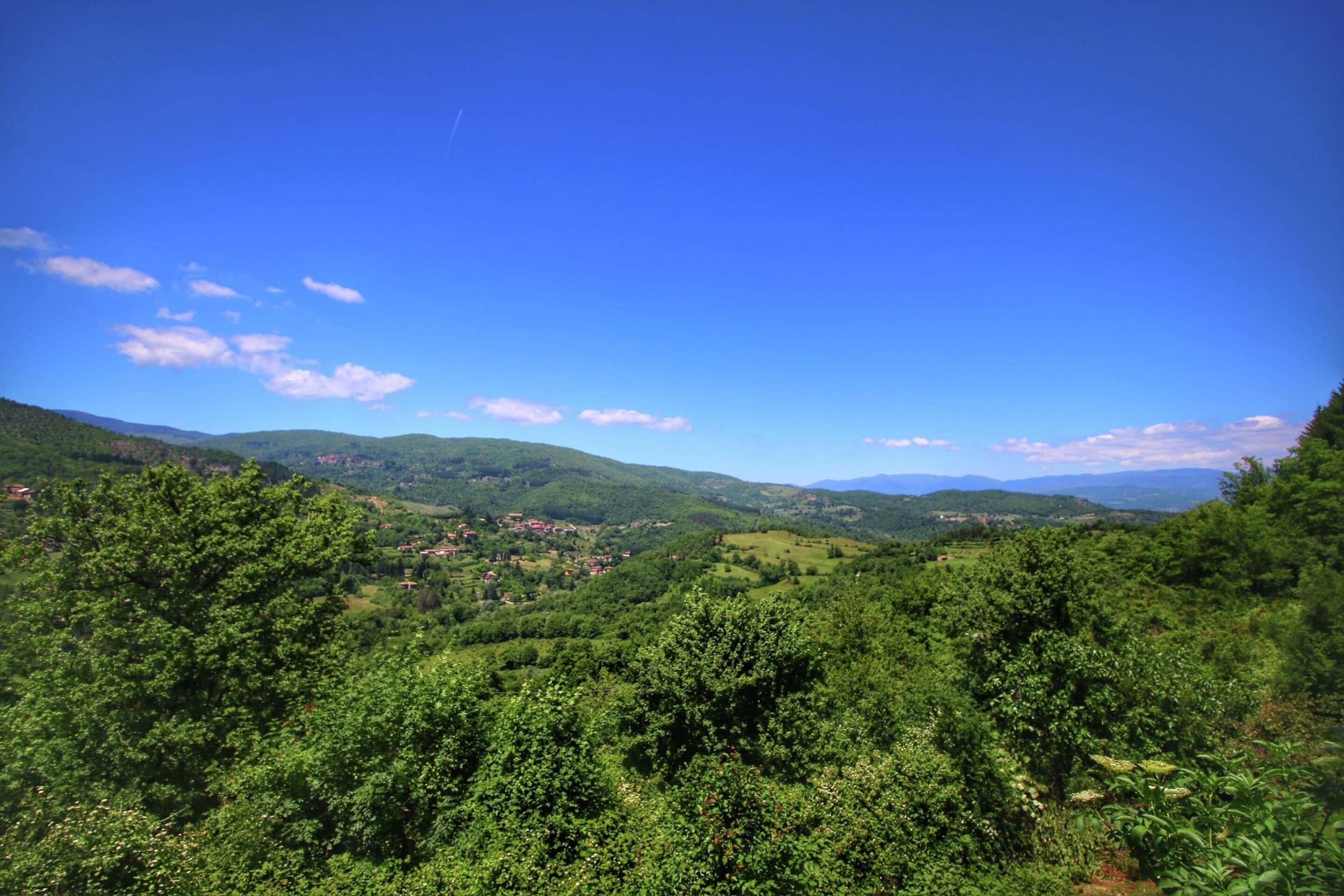 Egy buja, zöld völgyre nyíló, lenyűgöző panoráma, melyet hullámzó dombok és tiszta, kék ég ural.