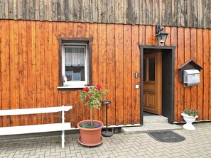 A wooden building with a bench, a potted plant, a mailbox, and a door. - Nice Apartment in Allrode With Private Terrace (Thale)