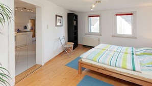 A bedroom with a wooden bed, a small chair, a radiator, and a window with a red blind. - Nice Apartment in Allrode With Private Terrace (Thale)