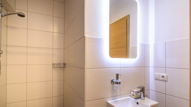 Une salle de bain moderne avec une douche, un lavabo et un miroir.
