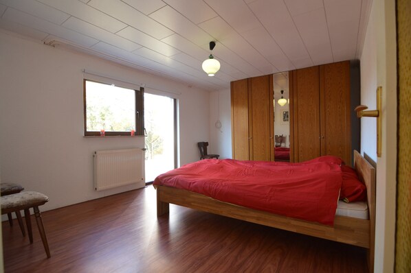 A bedroom with a wooden bed, a window, a radiator, and a wardrobe. - Pleasant Holiday Home in Kemmenau With Sauna (Bad Ems)
