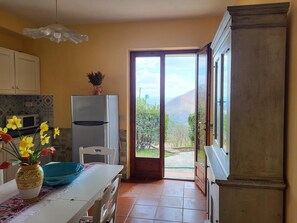 Una cocina con refrigerador, microondas y un florero con flores en la encimera.