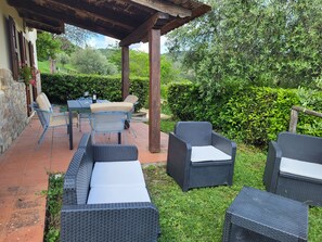 Eine Außenpatio mit Korbmöbeln, einem Tisch und einer Pergola.