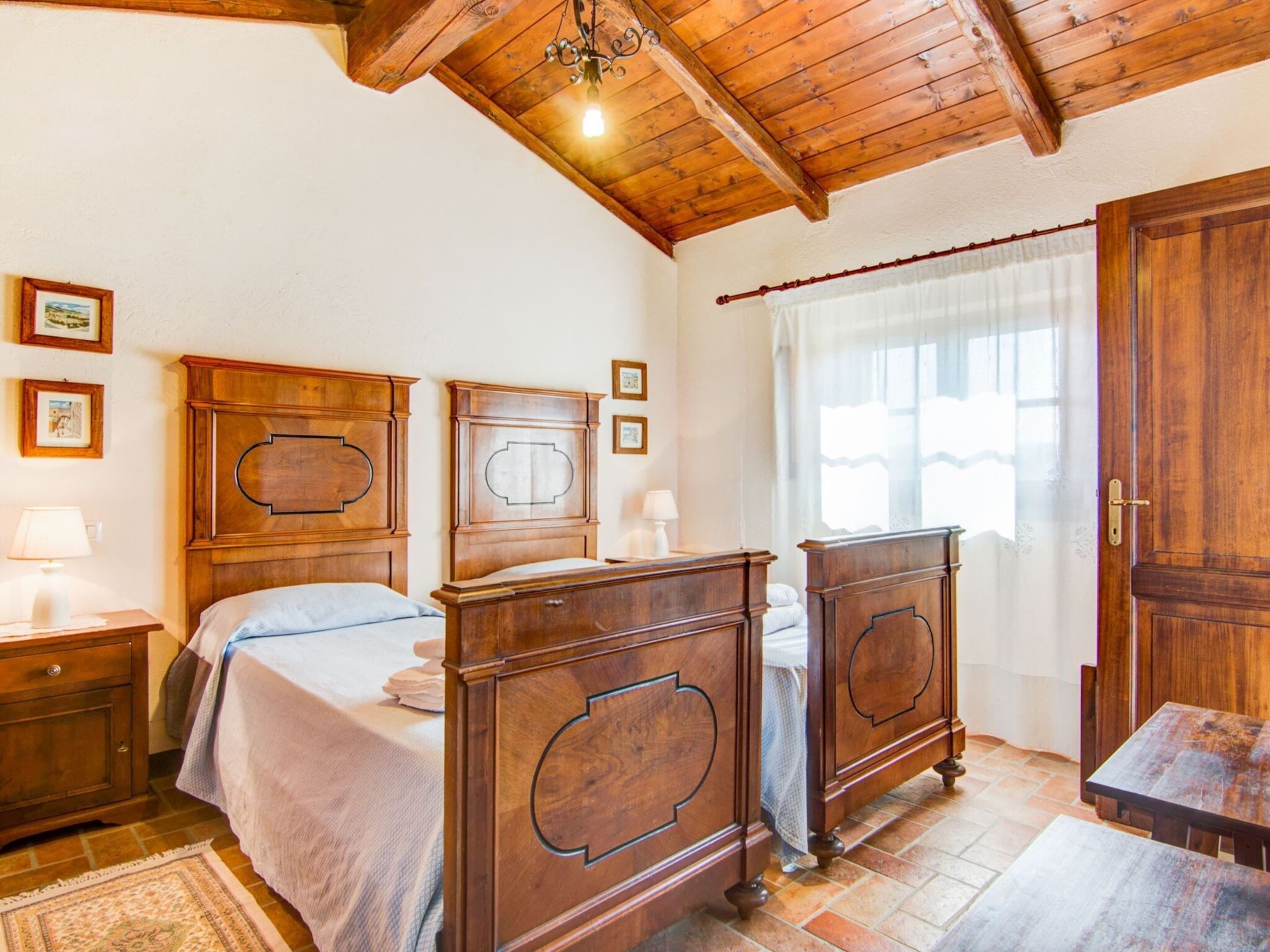 A traditional wooden bedroom with two beds, a wooden wardrobe, and a dining table.