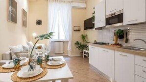 Une cuisine moderne avec des meubles blancs, un four encastré et un coin repas avec une table mise pour deux personnes.