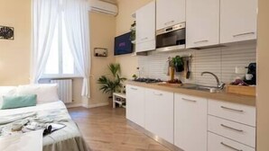 Une cuisine compacte avec des meubles blancs, un plan de travail en bois et un four encastré.