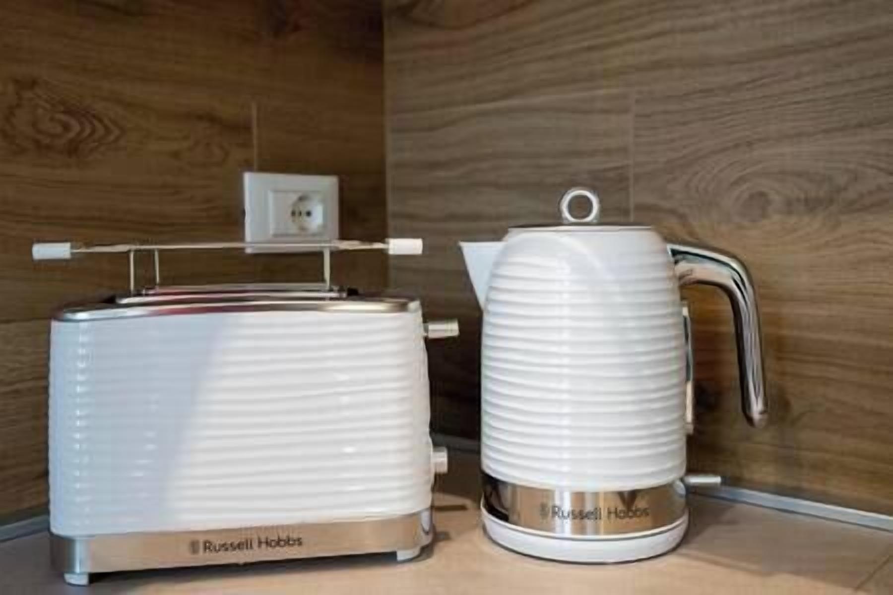 A kitchen with a toaster and a kettle on a wooden countertop.