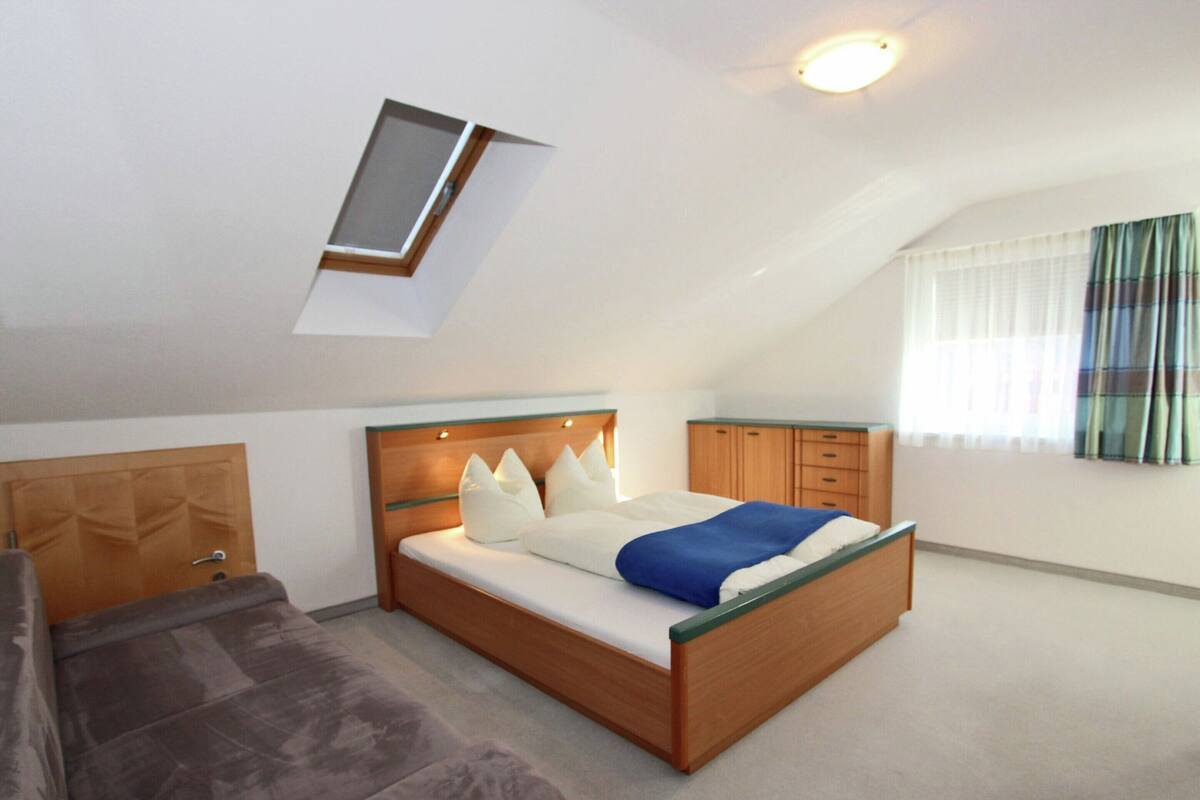 Een slaapkamer met een bed, een bank, een kledingkast en een dakraam.