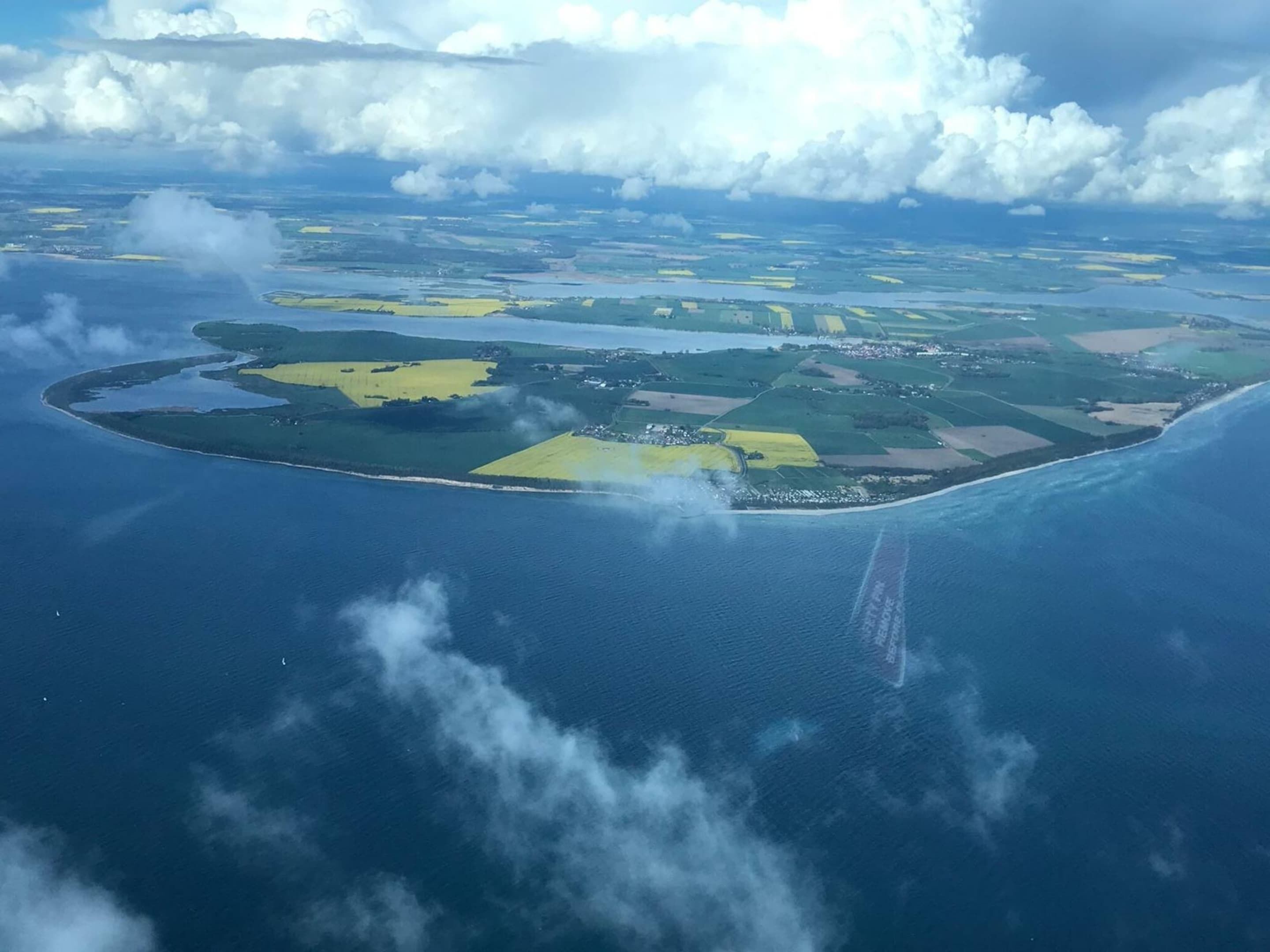 Eine Vogelperspektive einer kleinen Insel mit deutlich abgrenzbaren grünen und gelben Feldern, umgeben von Wasser.