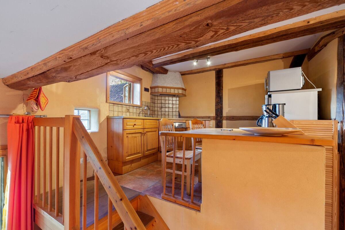 Eine gemütliche Küche mit Holzbalken, einer gefliesten Spritzschutzleiste und einer kleinen Essecke mit Tisch und Stühlen.