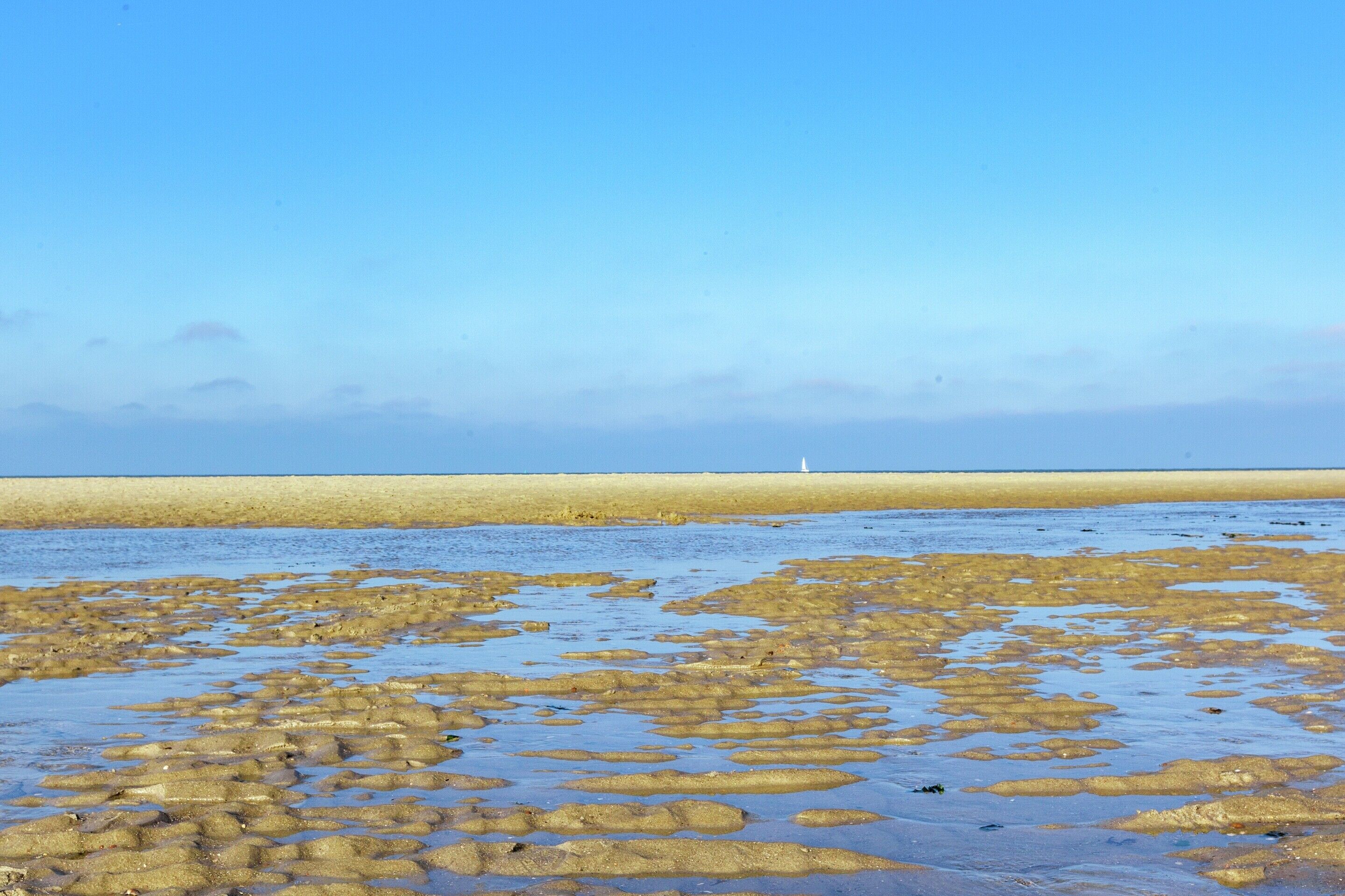 A beach with a sandy shore and a lighthouse in the distance.
