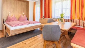 A modern room with a wooden bed, a dining table, and a bench. - Elegant Apartment in Saalbach-hinterglemm Near Ski Bus (Saalbach-Hinterglemm)
