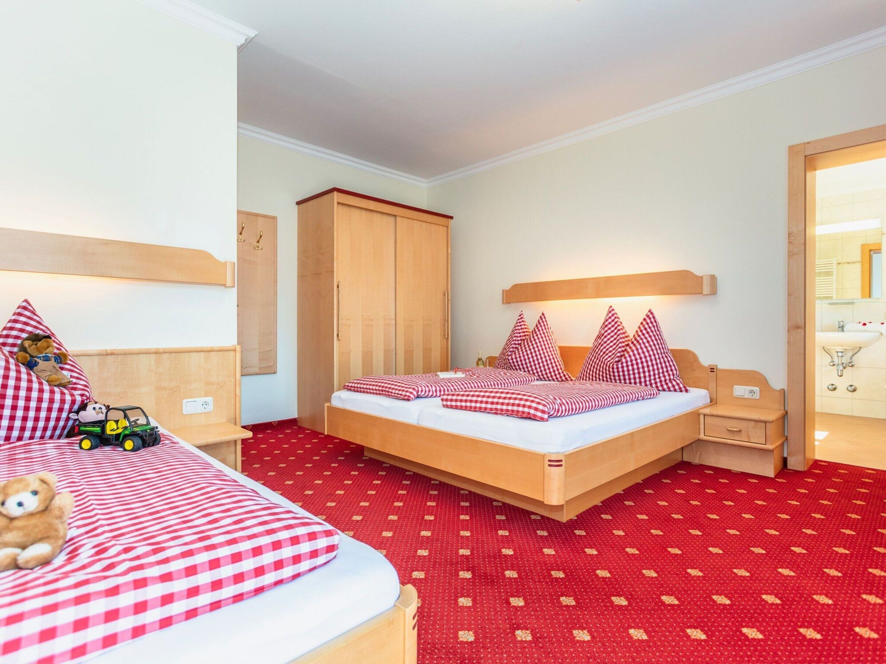 Habitación de hotel con cama, armario, mesita de noche y baño visible a través de una puerta abierta.