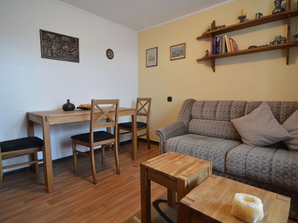 A living room with a wooden dining table, two chairs, a sofa, and a coffee table. - Appealing Apartment in Ittel With Garden, Parking, Bicycles (Welschbillig)