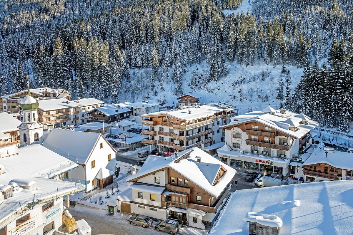 A snow-covered ski resort with multiple buildings, including a hotel with a ski lift visible.