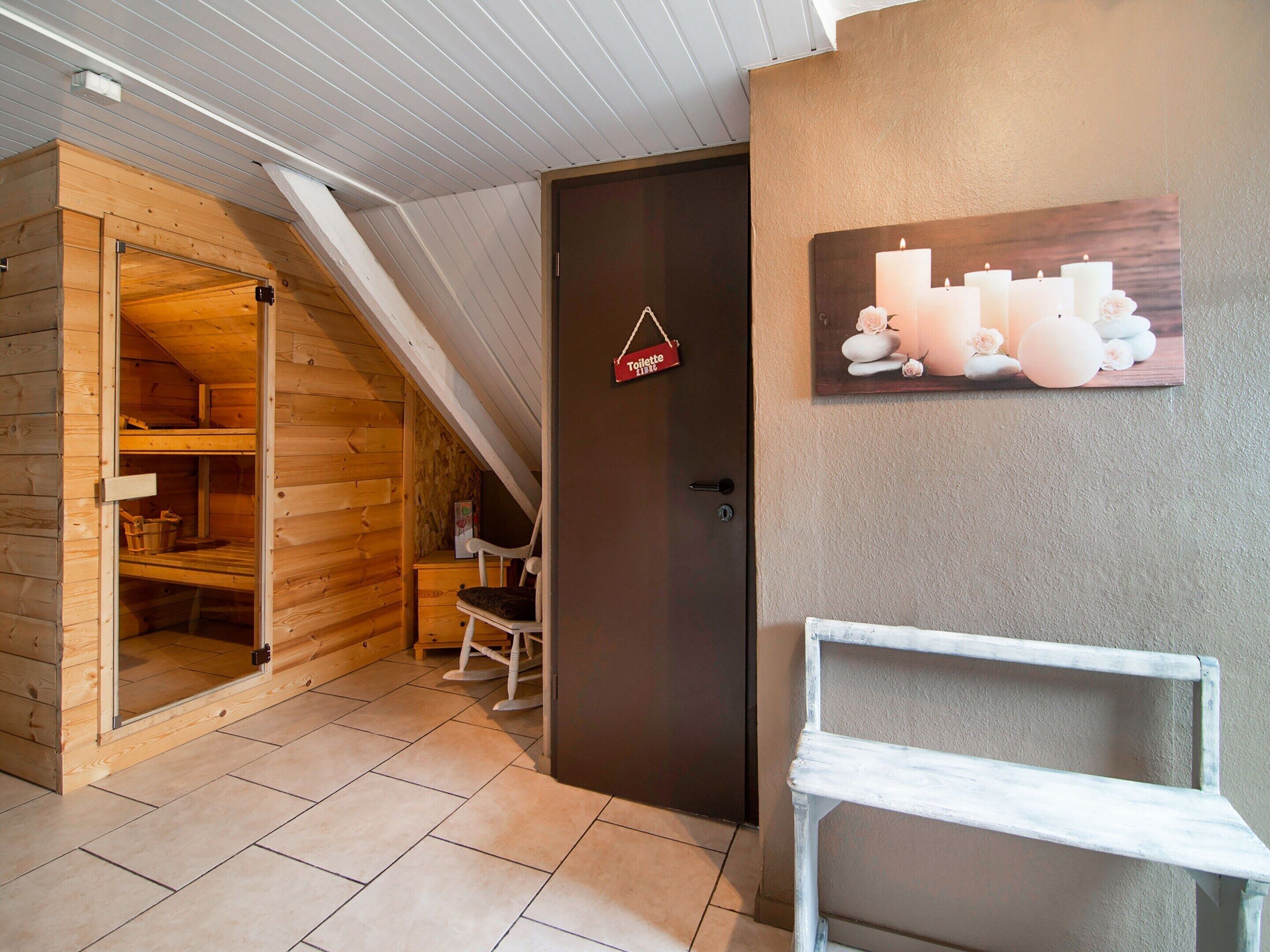 A wooden interior with a sauna room, a door with a toilet sign, and a shelf with candles.