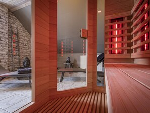 A modern interior with a wooden slatted wall, a stone wall, and a red-lit shelving unit. - Spacious Mansion in Waimes With Sauna (Waimes)