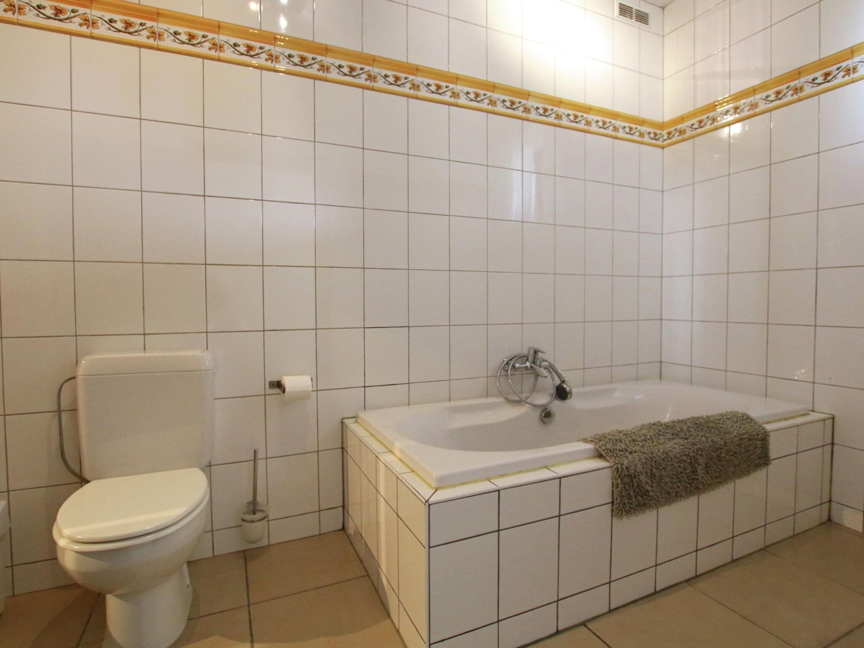 A bathroom with a toilet, a bathtub, and a shower.