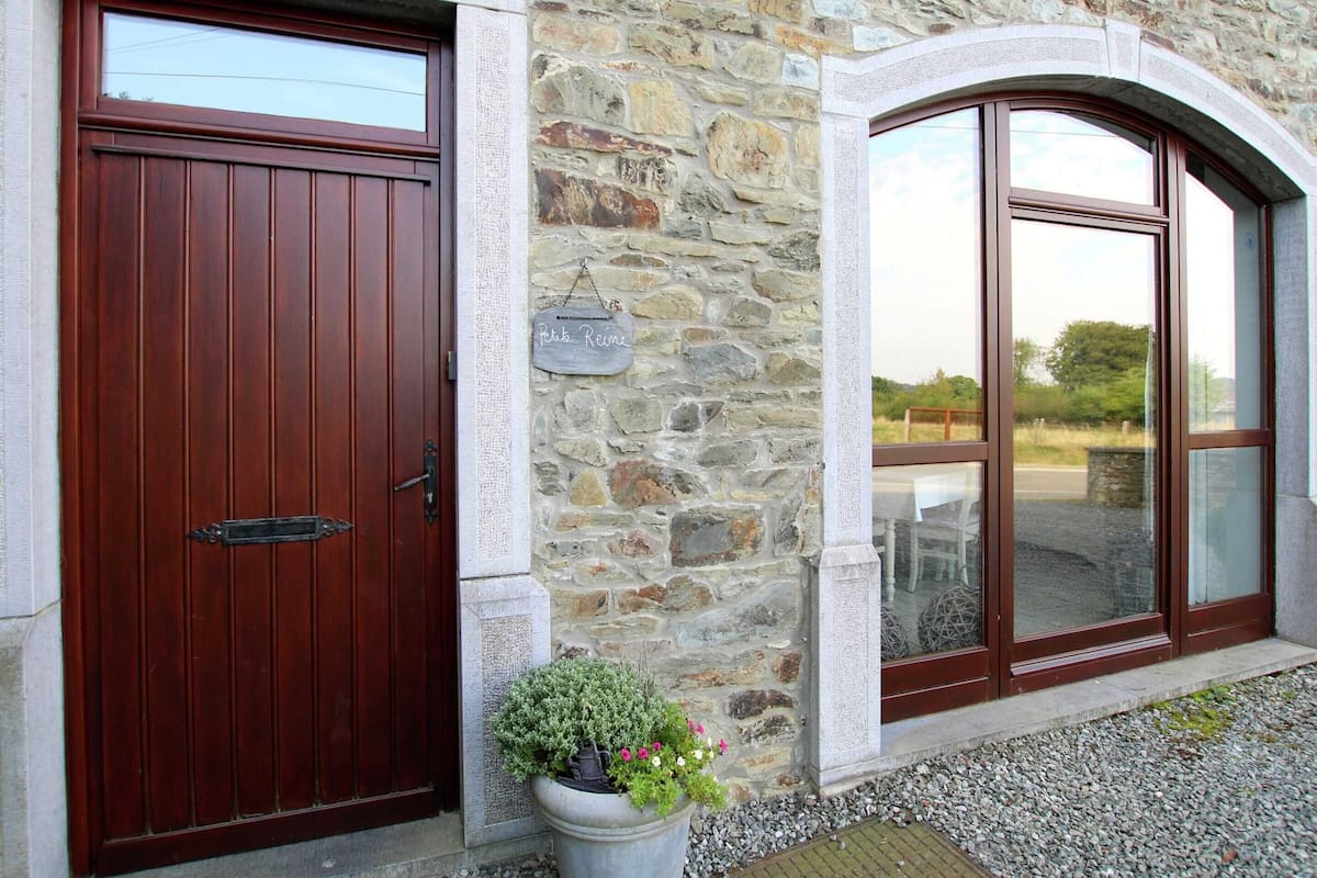 A stone building with a wooden door and a large arched window.