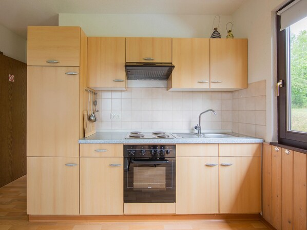 A compact kitchen with wooden cabinets, a stainless steel sink, and a built-in oven.
