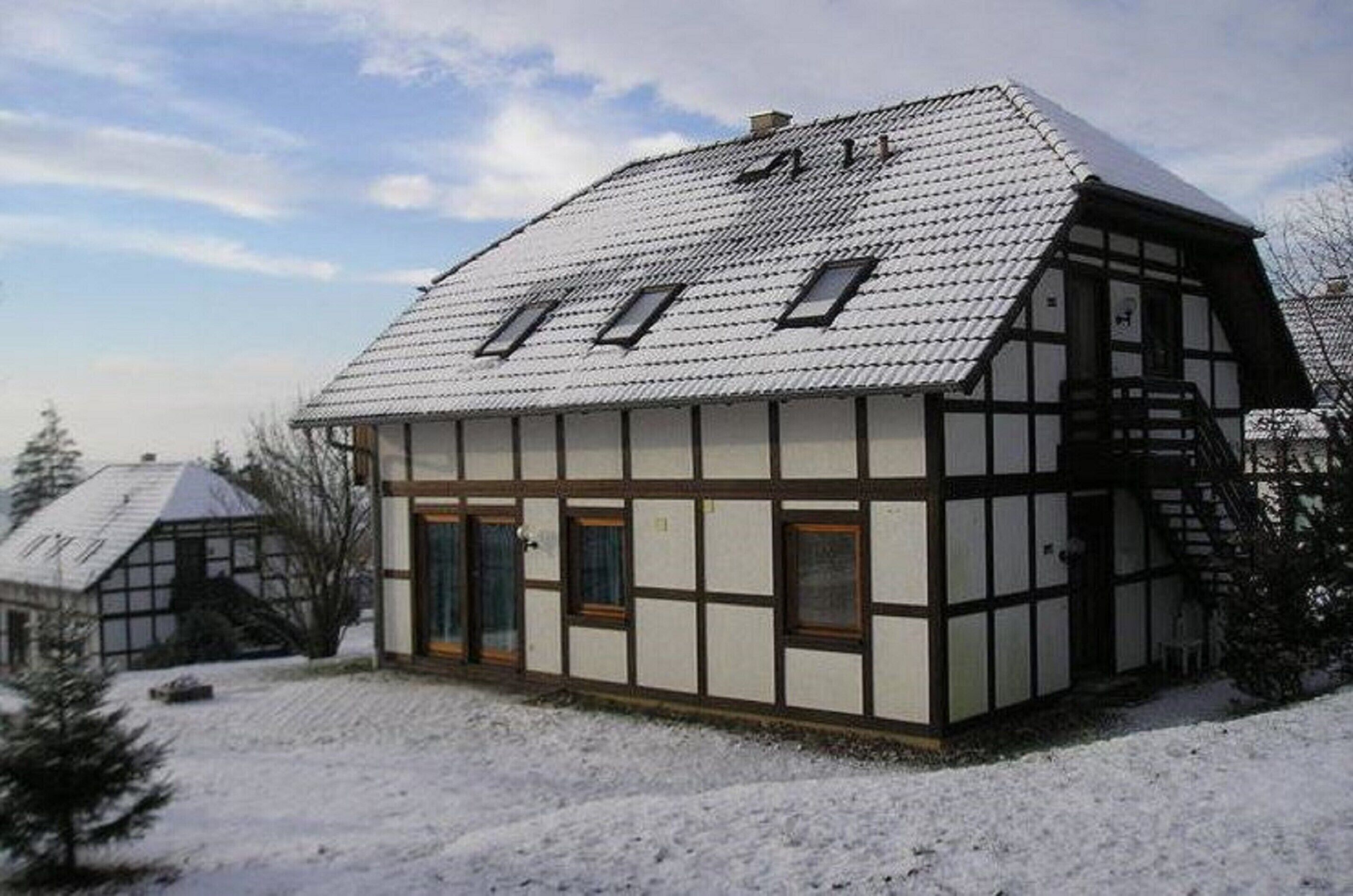A traditional half-timbered house with a steeply pitched roof and dormer windows.