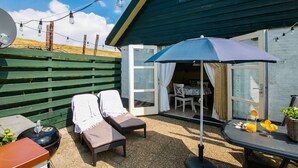 A patio with two lounge chairs, a table with drinks, and a blue umbrella. - Beautiful Apartment in Callantsoog Near Beach (t Zand)
