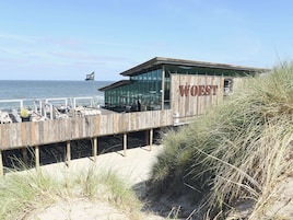 A coastal building with the name "WOEST" on its facade, overlooking the sea.