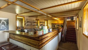 A bar area with wooden counters, shelves with glasses and bottles, a clock on the wall, and a staircase leading upstairs. - Cushy Boat in Merkem With Terrace (Houthulst)
