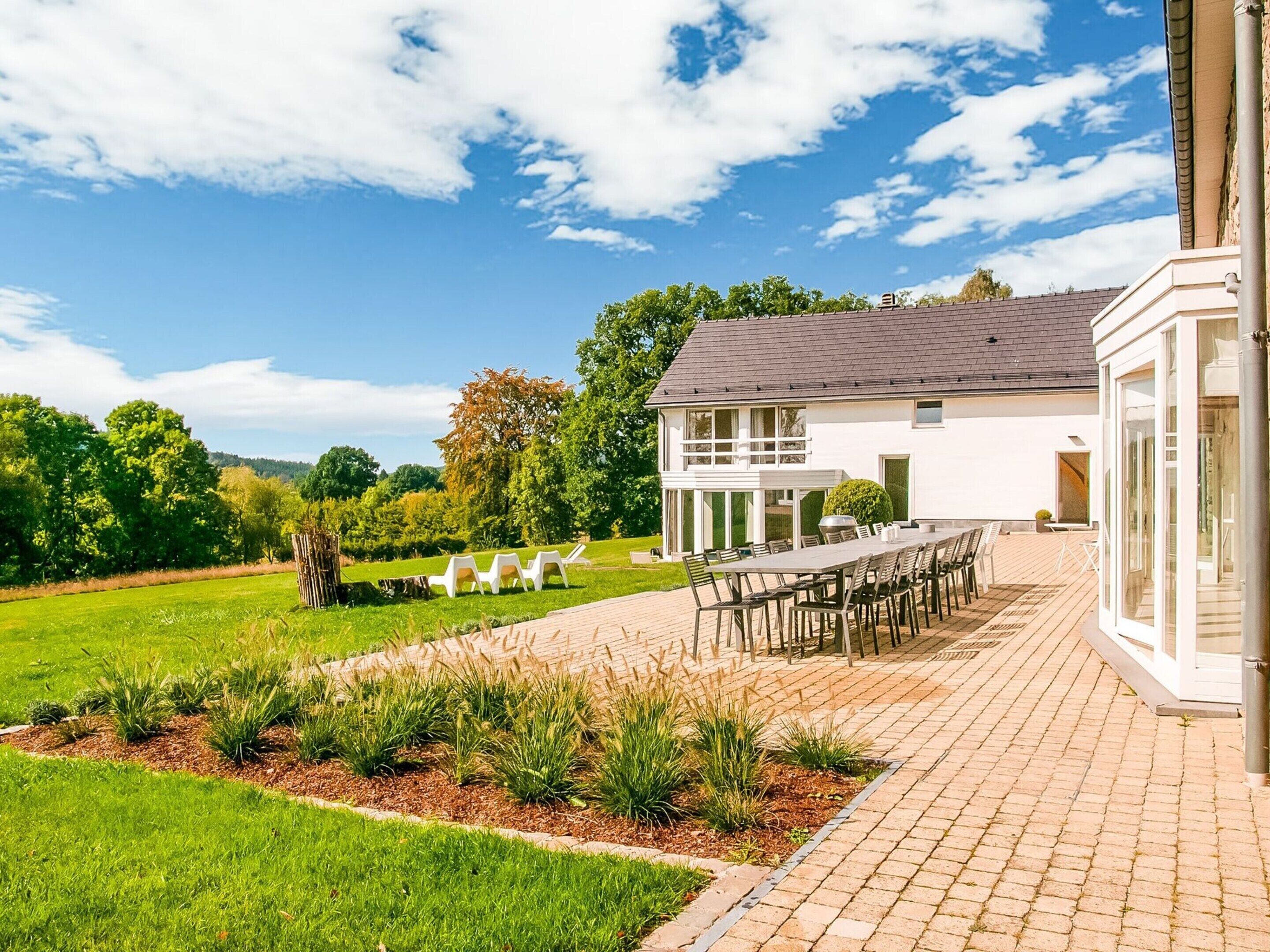 A two-story house with a patio area, outdoor seating, and a well-maintained garden.