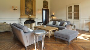 Un salon spacieux avec une cheminée, un grand tableau et un coin salon confortable avec des canapés et une table basse.