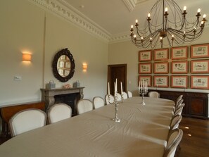 A formal dining room with a long table, chairs, a chandelier, a fireplace, and framed pictures on the wall. - Luxurious Castle in Marchin With Infrared Sauna (Marchin)