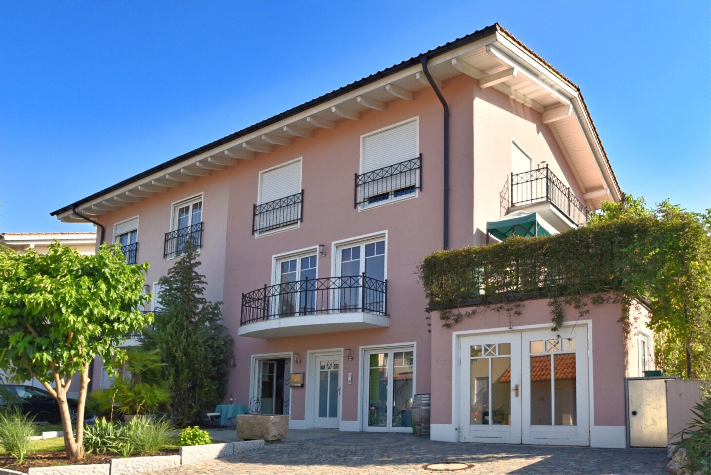 A pink building with a balcony, a door, and a window.