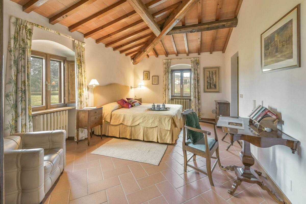 Une chambre confortable avec un plafond en bois, un lit avec des oreillers, un bureau et une chaise.