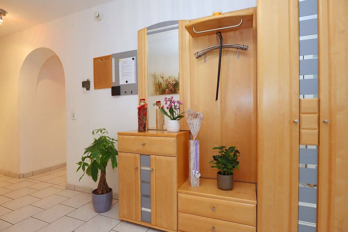A wooden cabinet with a mirror, a towel rack, and a potted plant.